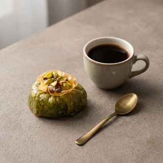 Pistachio Ring Baklava beside a coffee cup showing size