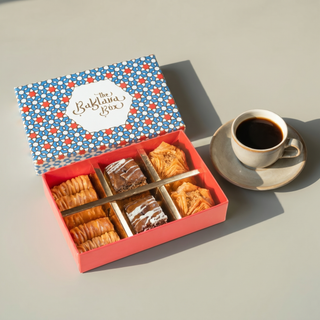 Open Baklava Box six-piece sampler beside a cup of coffee